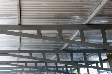 Çelik yapının üzerine eski kiremit çatının yerine gri metal levhalar döşenmiş. Aşağıdan çatıya doğru açı, gökyüzünü görmek..