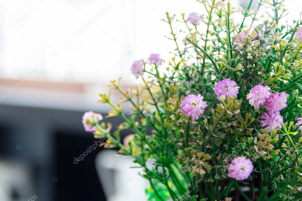 Choose focus on the flower pot. Colorful fake flowers with green leaves in the basket A bucket on a brown wooden table in a coffee shop in the morning Plastic flower pot Home interiors, offices and living room decor