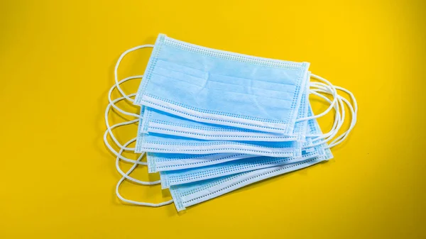Mikropları önlemek, sarı arkaplandaki virüsleri önlemek için tıbbi kullanım maskesi.