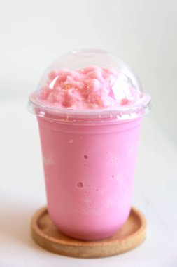 Çilekli bardak, ahşap bardak altlıkları ve beyaz arka plan.