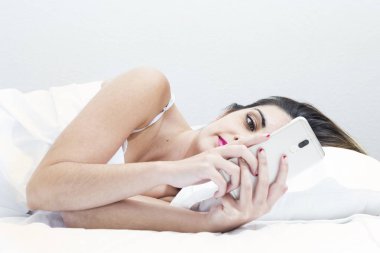 Beyaz yatakta kadınla onun elinde bir konfor duruş içinde belgili tanımlık hareket eden.