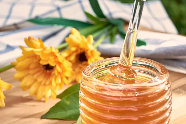 Honey dripping from a spoon of honey on bamboo wood. — Stock Photo, Image