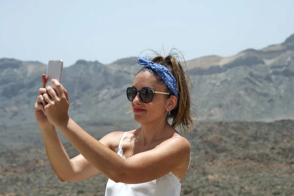 Beautiful woman doing a selfie on top of a mountain. — Stock Photo, Image