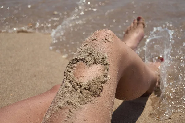 sand heart drawn on the leg of a girl.