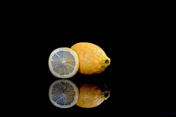 Plano de limones enteros y cortados en rodajas aislados sobre fondo negro — Foto de Stock