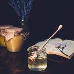 Selektiver Fokus des Glases mit Honigstange und Lavendel auf schwarzem Hintergrund
