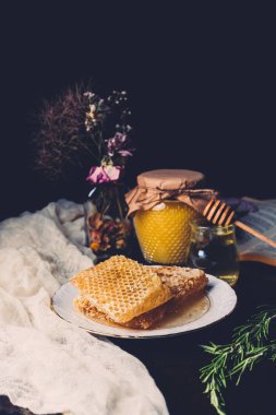 kavanoz bal, peteğin ve siyah arka plan üzerine kuru çiçekler ile seçici odak 