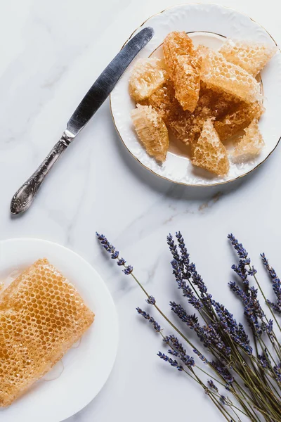 Top view of knife, plates with honeycombs and lavender on marble table — Stock Photo