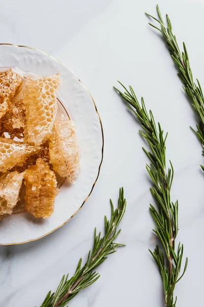 Top view of plate with honeycombs and rosemary on marble table — Stock Photo