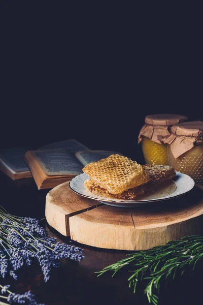 Foyer sélectif de lavande, romarin, nids d'abeilles et des pots avec du miel sur fond noir — Photo de stock