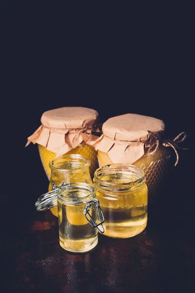Selective focus of different jars with honey on black background — Stock Photo