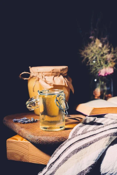 Selective focus of jars with honey on cutting board on black background — Stock Photo