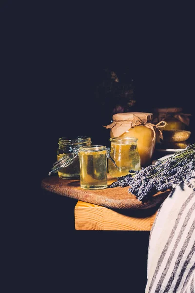 Selective focus of lavender and different jars with honey on black background — Stock Photo