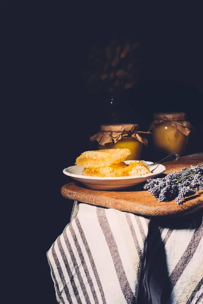 Selektiver Fokus von Lavendel, Gläsern und Waben auf Teller auf schwarzem Hintergrund — Stockfoto