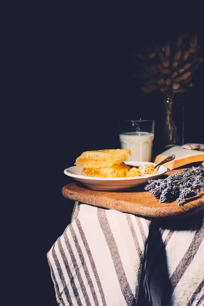 Selective focus of glass of milk, honeycombs and lavender on table on black background — Stock Photo