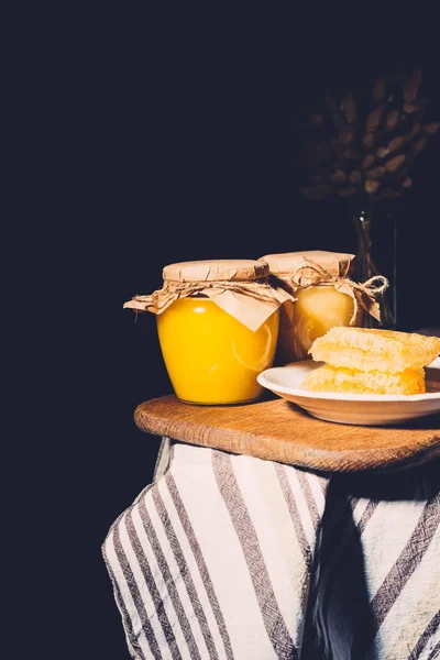 Selective focus of honeycombs and jars with honey on black background — Stock Photo