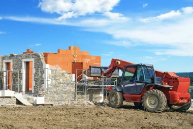 Teleskopik vinç kullanılarak taş kaplı tuğla ev inşaatı.                      