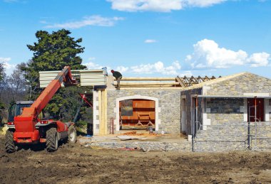 Teleskopik vinç kullanılarak çatıya yalıtım elemanlarının montajı.                     