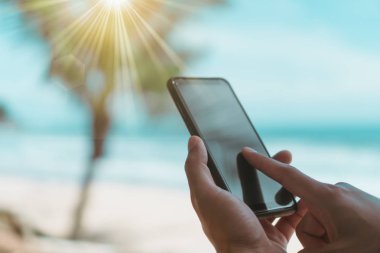 Yaz plaj güzel güneş ışığı ile önünde Smartphone kullanarak kadın ele.