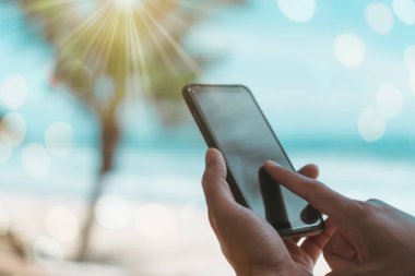 Yaz plaj güzel güneş ışığı ile önünde Smartphone kullanarak kadın ele.