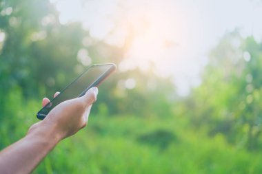 Yeşil Doğa arka plan ile Smartphone kullanarak kopya alan Bayan ele.