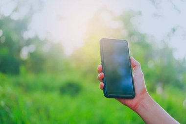 Yeşil Doğa arka plan ile Smartphone kullanarak kopya alan Bayan ele.
