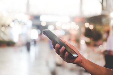 Kadın el ile renkli bokeh açık renkli alışveriş merkezinde Smartphone kullanarak.