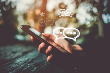 Kadınlar akıllı telefon daktiloyla yazı yazıp sohbet ediyorlar. Sohbet kutusu simgeleri ortaya çıkıyor. Sosyal medya teknolojisi kavramı. Klasik yumuşak renk tonu arkaplanı.