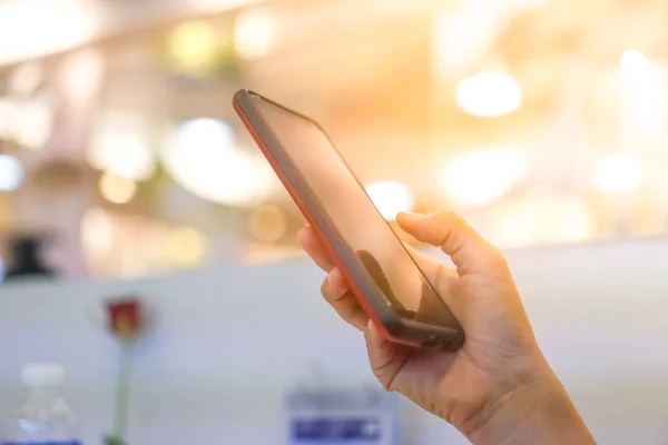 妇女手使用智能手机在商场与彩色散景光背景 — 图库照片
