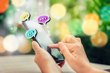 Kadınlar akıllı telefon daktiloyla yazı yazıp sohbet ediyorlar. Sohbet kutusu simgeleri ortaya çıkıyor. Sosyal medya teknolojisi kavramı. Klasik yumuşak renk tonu arkaplanı.