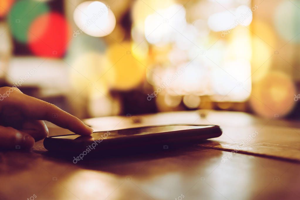 Woman hand using smartphone and laptop with cafe shop colorful beautiful bokeh background. Business, financial, trade stock maket and social network concept.