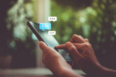 Kadınlar akıllı telefon daktiloyla yazı yazıp sohbet ediyorlar. Sohbet kutusu simgeleri ortaya çıkıyor. Sosyal medya teknolojisi kavramı. Klasik yumuşak renk tonu arkaplanı.