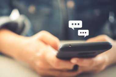 Kadınlar akıllı telefon daktiloyla yazı yazıp sohbet ediyorlar. Sohbet kutusu simgeleri ortaya çıkıyor. Sosyal medya teknolojisi kavramı. Klasik yumuşak renk tonu arkaplanı.