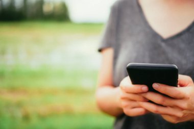 Kadın el doğa ile Smartphone kullanarak yeşil güzel arka plan. İş, finans, Ticaret hisse senedi maket ve sosyal ağ kavramı.