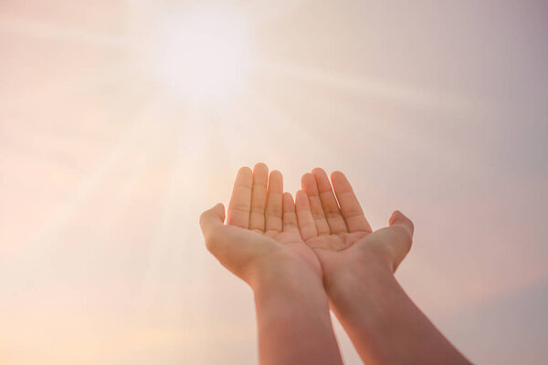Woman hands place together like praying in front of nature green  background.