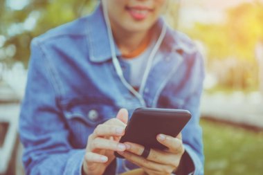 Kadın el Smartphone ve gülümseme kullanarak eğlenceli doğa ile hissediyorum yeşil güzel arka plan. İş, finans, Ticaret hisse senedi maket ve sosyal ağ kavramı.