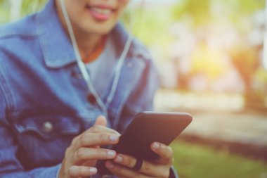 Kadın el Smartphone ve gülümseme kullanarak eğlenceli doğa ile hissediyorum yeşil güzel arka plan. İş, finans, Ticaret hisse senedi maket ve sosyal ağ kavramı.