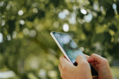 Kadın el doğa ile Smartphone kullanarak yeşil güzel arka plan. İş, finans, Ticaret hisse senedi maket ve sosyal ağ kavramı.