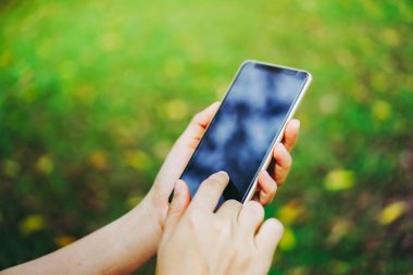 Kadın el doğa ile Smartphone kullanarak yeşil güzel arka plan. İş, finans, Ticaret hisse senedi maket ve sosyal ağ kavramı.