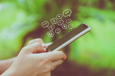 Kadınlar akıllı telefon daktiloyla yazı yazıp sohbet ediyorlar. Sohbet kutusu simgeleri ortaya çıkıyor. Sosyal medya teknolojisi kavramı. Klasik yumuşak renk tonu arkaplanı.