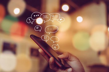 Kadınlar akıllı telefon daktiloyla yazı yazıp sohbet ediyorlar. Sohbet kutusu simgeleri ortaya çıkıyor. Sosyal medya teknolojisi kavramı. Klasik yumuşak renk tonu arkaplanı.