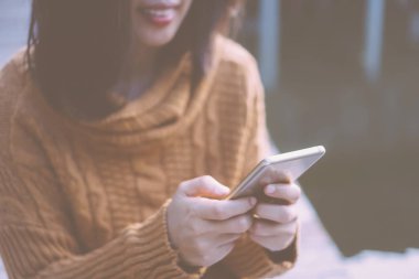 Kadın el Smartphone ve gülümseme kullanarak eğlenceli doğa ile hissediyorum güzel arka plan. İş, finans, Ticaret hisse senedi maket ve sosyal ağ kavramı.