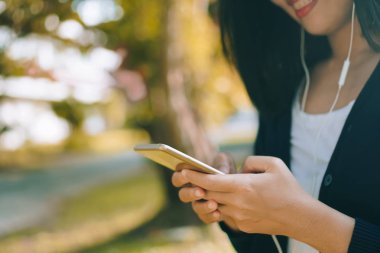 Kadın el Smartphone ve gülümseme kullanarak eğlenceli doğa ile hissediyorum güzel arka plan. İş, finans, Ticaret hisse senedi maket ve sosyal ağ kavramı.