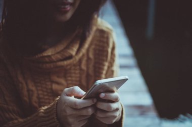 Kadın el Smartphone ve gülümseme kullanarak eğlenceli doğa ile hissediyorum güzel arka plan. İş, finans, Ticaret hisse senedi maket ve sosyal ağ kavramı.