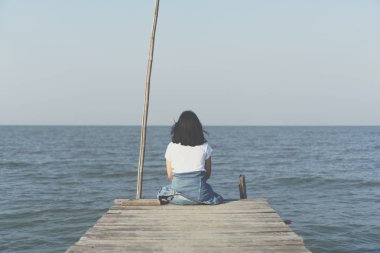 Kadın yalnız köprü Özgürlük kavramı mavi gökyüzü ve yaz alan arka plan üzerinde oturuyor.