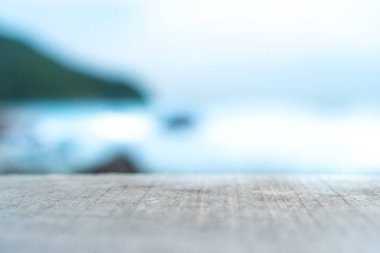 Ürününüzü göstermek için güzel plaj arka planına sahip eski ahşap masanın seçici odağı. 