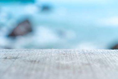 Ürününüzü göstermek için güzel plaj arka planına sahip eski ahşap masanın seçici odağı. 