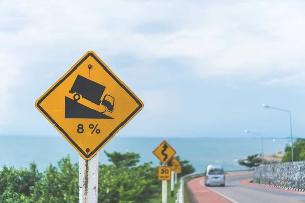Traffic sign show beside road with beach view background.