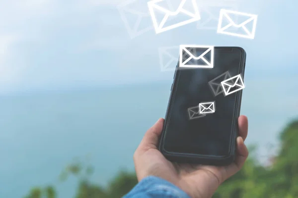 Woman hand using smartphone to send and recieve email for business on bokeh vintage color tone background.