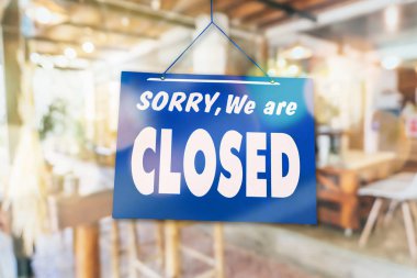 Kapalı olduğumuz için üzgün olduğumuzu belirten bir pano doğa yeşili arka planlı bir atölyenin kapısına asıldı.